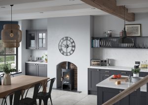 Kendal Indigo shaker kitchen space with clock, fireplace and wooden table. Made by The Kitchen Depot