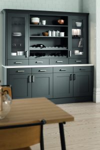 Anthracite shaker units create a modern twist in this traditional kitchen design. Olympia shaker doors are used in all kitchen units. An anthracite dressed is shown here, showing smart storage of cups, bowls and mugs. The unit has a mix of glass fronted units, down the left and right of the unit. In the middle there is open shelving with trinkets and bowls placed on it. The bottom section has 4 drawers and 4 cupboard doors revealing 2 cupboard storage spaces.