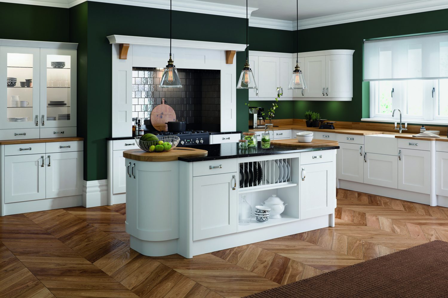 A beautifully traditional style with a modern twist, this kitchen design include Olympia white shaker doors and kitchen units. The design is L shaped with a kitchen island with curved units. The Kitchen island has glass lighting over head. The walls in the room are deep green, with wooden herringbone flooring. The worktops over by the sink are wooden, the sink is a white Belfast sink with a Chrome tap.
