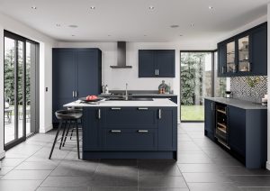 Skye shaker kitchen door is showcased in this modern kitchen. Indigo blue doors are on all kitchen units, with white marble worktops and wooden stools on the kitchen island. Double glass doors open into the garden.