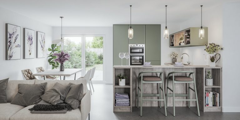 A discovery kitchen range is shown with Reed Green and Taupe units, wooden kitchen island and with shelving either side containing potted plants, cook books and lavender blankets. In the seating ares of the island between the shelving there are 2 reed green bar stools. Above the kitchen island are 3 lantern lights. The back units are Reed green and true handleless tall units with a stainless steel double oven placed in the middle of the units. To the left there is a wooden table with 4 white chairs with green cushions, behind here there are double glass doors in the garden where you can see some hedging and the grass. Just in front of the table is a cashmere couch with grey cushions and lavender flowers on top of the table as well as lavender pictures hanging on the wall to the left.