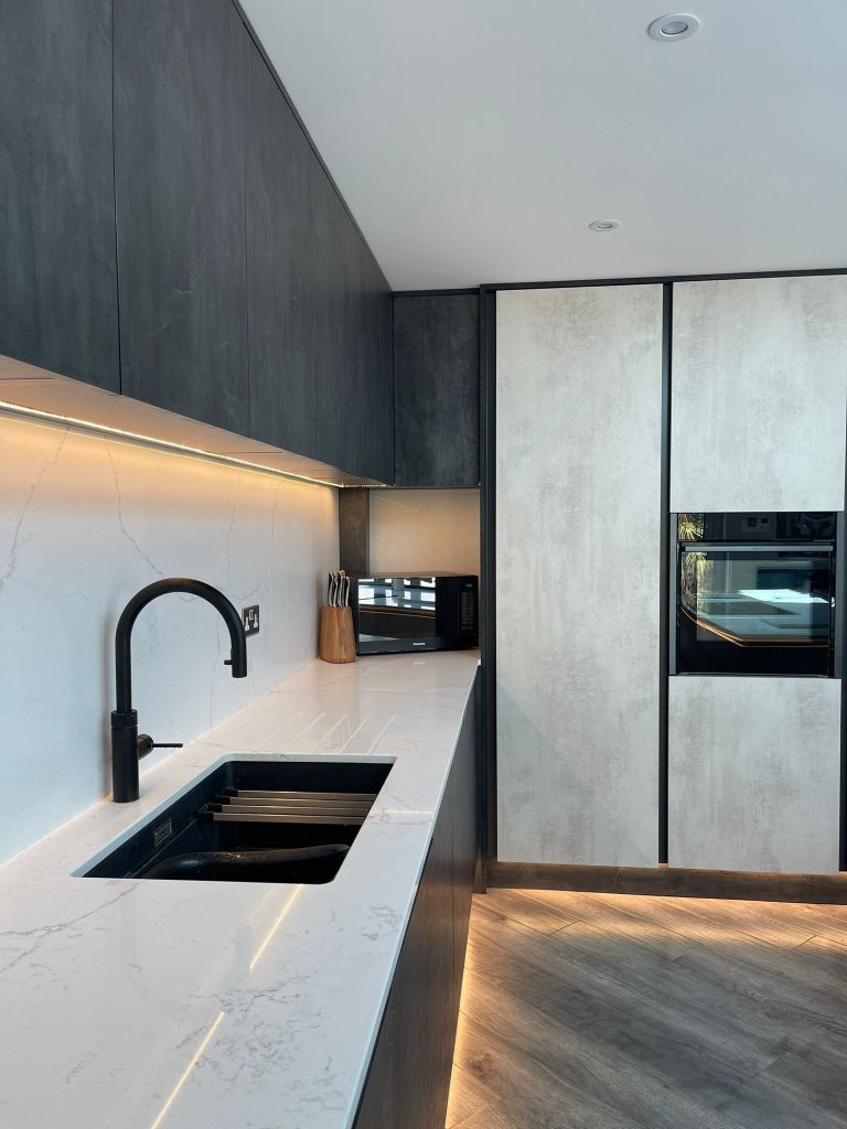 Sink, tap, and oven from the Midwinter's open plan kitchen featuring Linea White Chromix and Silver Metal Slate doors