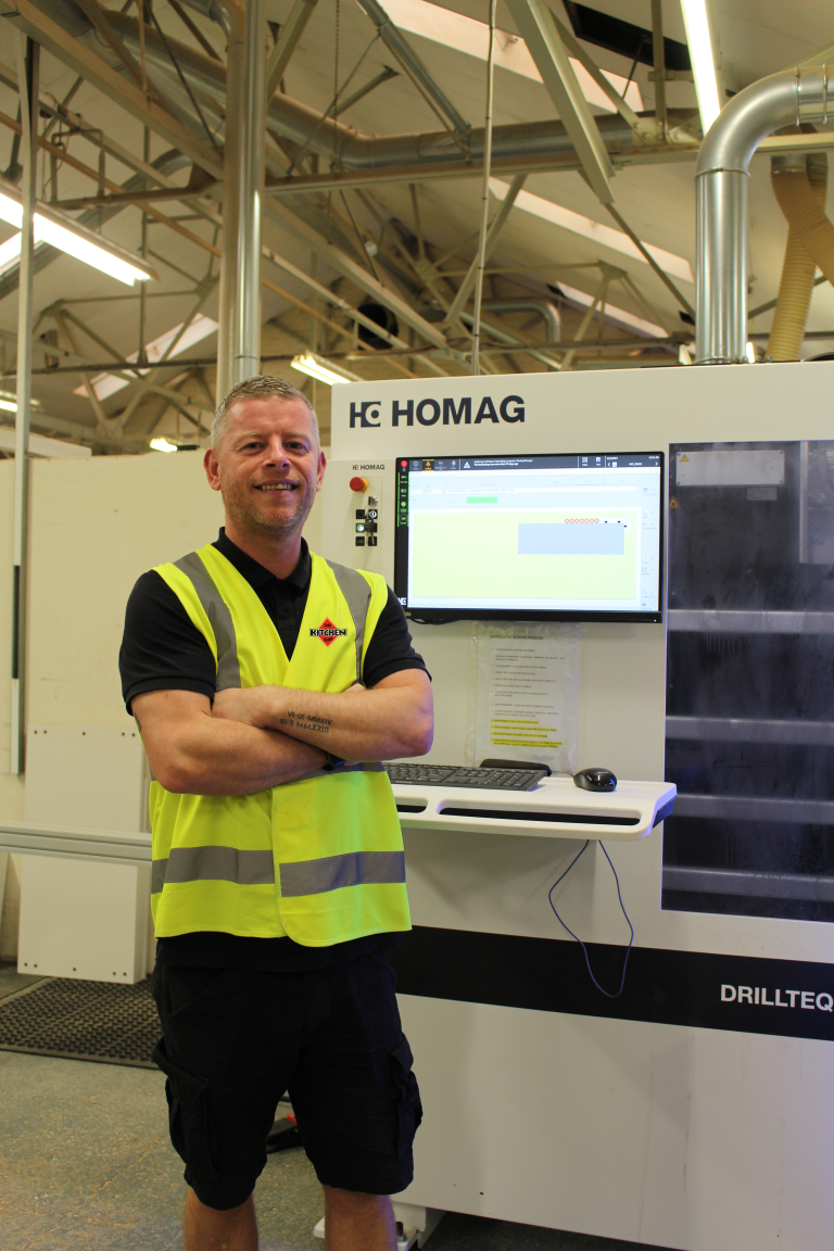 The Kitchen Depot's manufacturing manager standing in the The Kitchen Depot's kitchen factory in Glasgow beside a CNC machine used to make kitchens